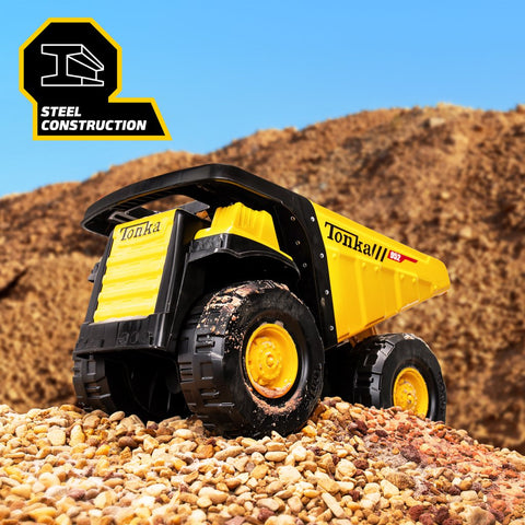 Yellow toy dump truck with steel construction on gravel with dirt piles in background