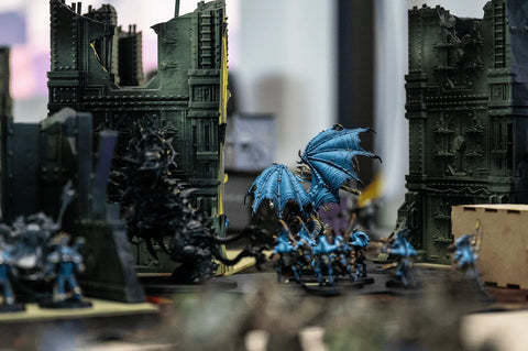 Tabletop miniature wargame figures with blue dragon and ruined building terrain