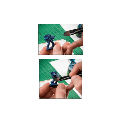 Person using a large paintbrush to paint a blue tabletop miniatures figure on a work mat