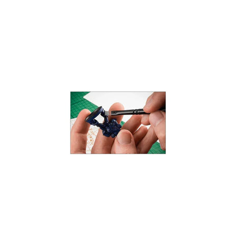 Hand painting miniature figure with detail brush on tabletop crafting mat