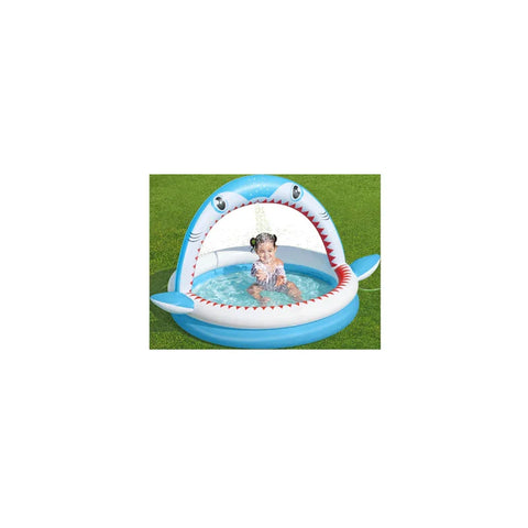 Child playing in inflatable shark sprinkler pool on green grass