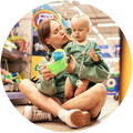 Woman and child sitting on the floor in a store aisle with toys around