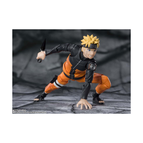 Anime action figure in orange ninja outfit holding kunai on rocky background, collectible toy.