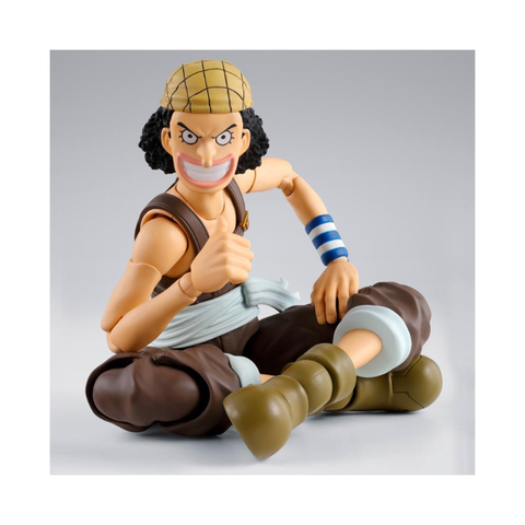 Anime action figure with curly hair, brown pants, green boots, and blue-striped wristband.