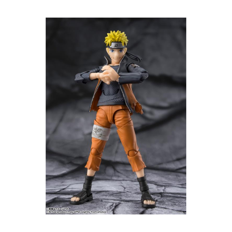 Anime action figure with spiky yellow hair, orange outfit, and headband on textured background