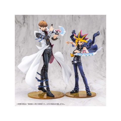 Anime figure toys of two duelists with trading cards and duel disk stands on display